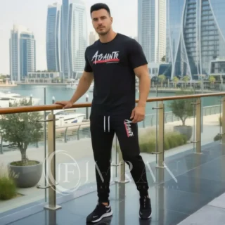 Model wearing Full 2-piece AGAINTS Urban Series Tracksuit fro men`s featuring a midnight-black"AGAINTS" graphic t-shirt and onyx black joggers on th roof top of skyline buliding