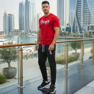 Model wearing Full 2-piece AGAINTS Urban Series Tracksuit for men`s featuring a Crimson Red "AGAINTS" graphic t-shirt and onyx black joggers on th roof top of skyline buliding